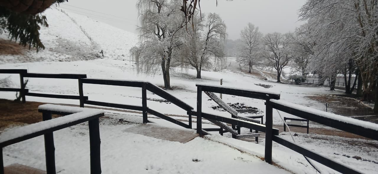 A snow-covered outdoor area with a wooden bench and a metal railing.