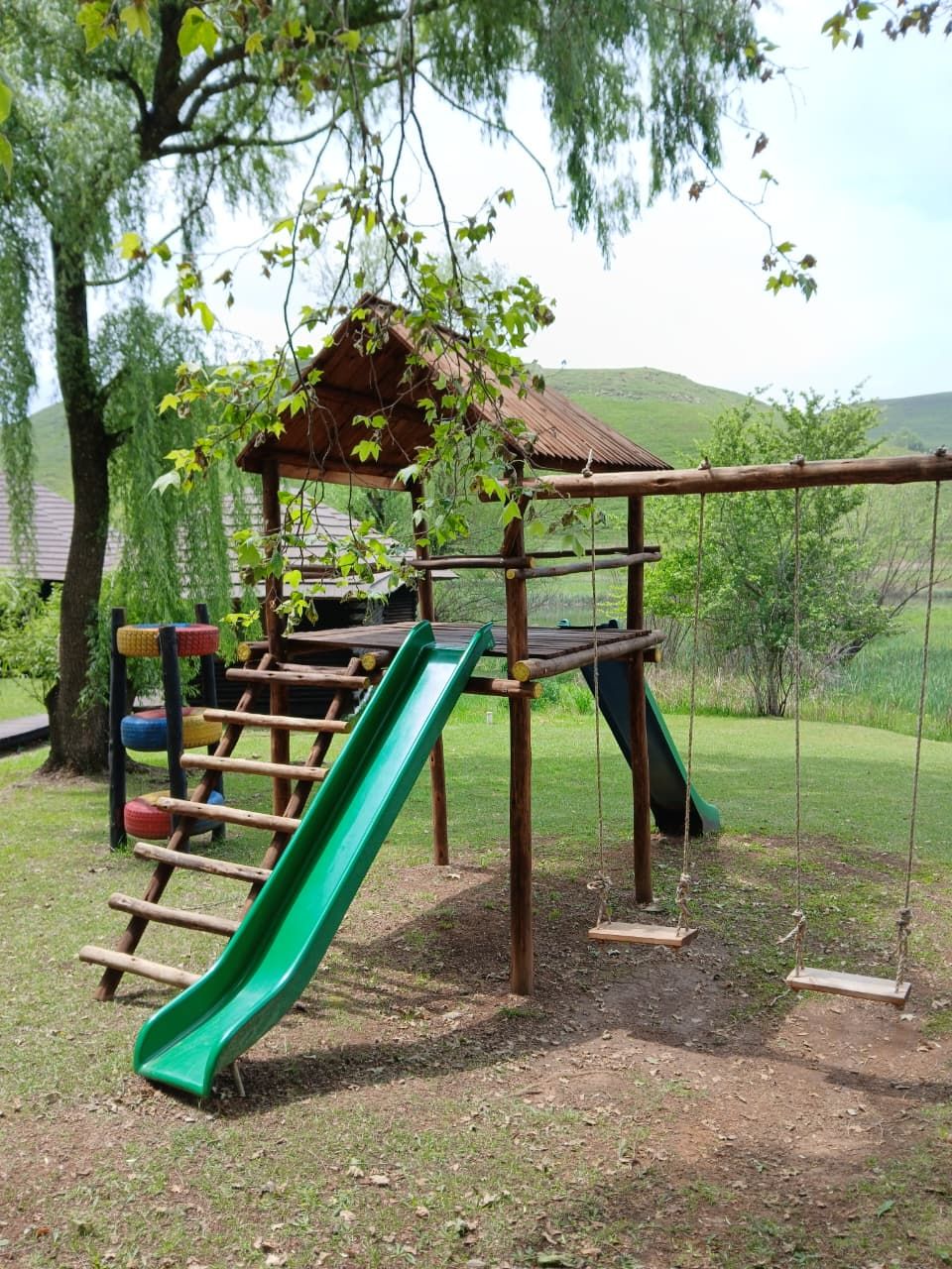 Ein Spielplatz mit Rutsche, Schaukeln und einer Kletterkonstruktion.