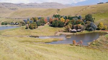 Un paisaje rural con un lago, colinas onduladas y árboles dispersos.