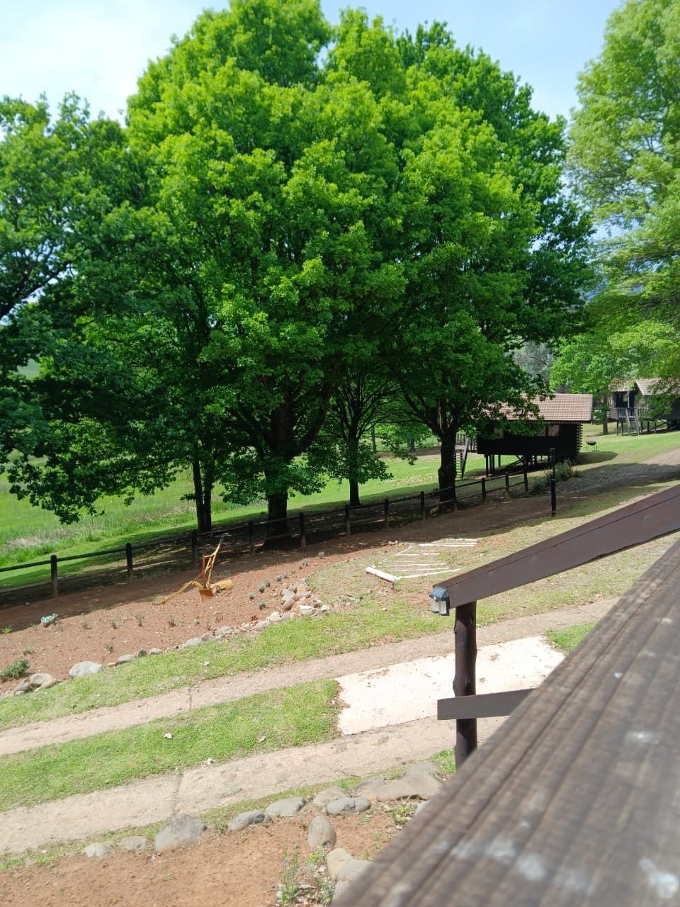 A park with a picnic area, a wooden bench, and a fenced area with trees.
