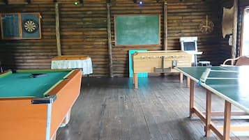Un interior de madera con mesa de billar, mesa de ping pong y una pizarra.