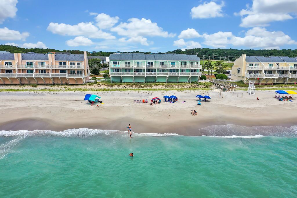 A beachfront hotel with multiple balconies, a sandy beach, and clear turquoise waters.