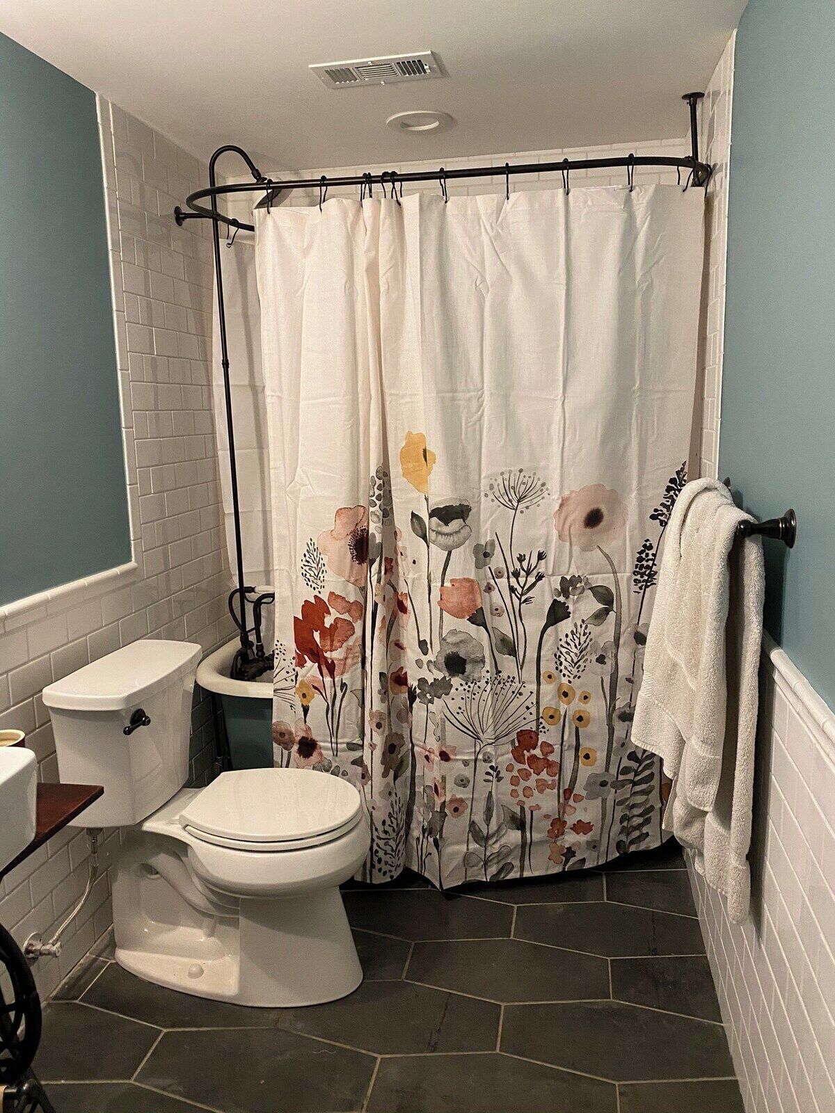 Une salle de bain avec des toilettes blanches, un bidet et un rideau de douche à motifs floraux.