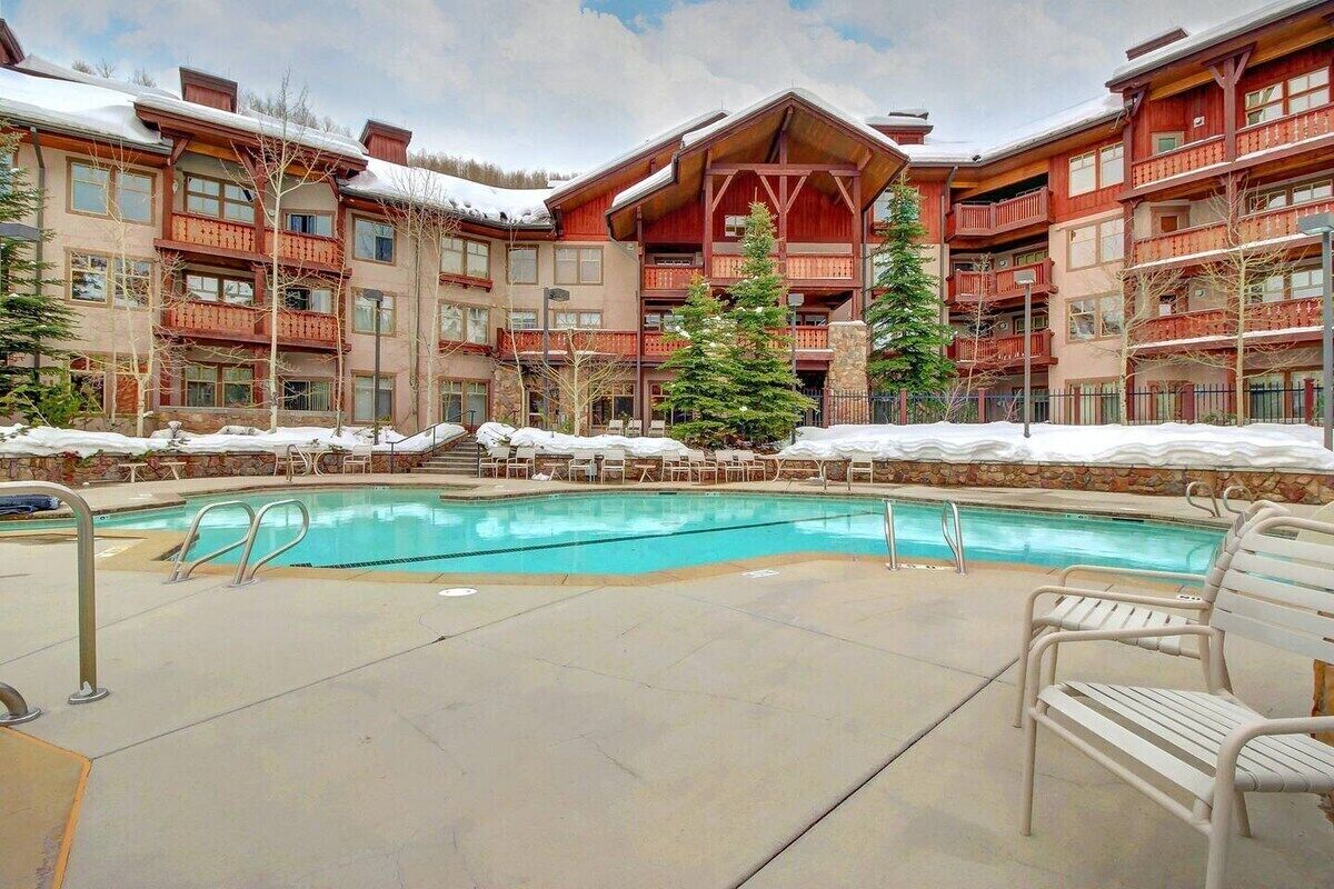A hotel with a pool, outdoor seating, and a snowy landscape.