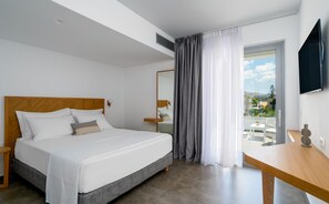Ett hotellrum med en säng, ett skrivbord, en tv och en balkong med utsikt.