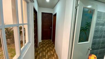 A hallway with patterned flooring, a wooden door, and a glass door with a tropical mural.