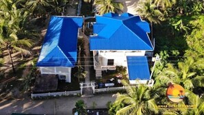 A resort with two buildings, each with a blue roof, surrounded by palm trees and a beach. - Lanas Beach Resort - Carabao Island (Carabao Island)