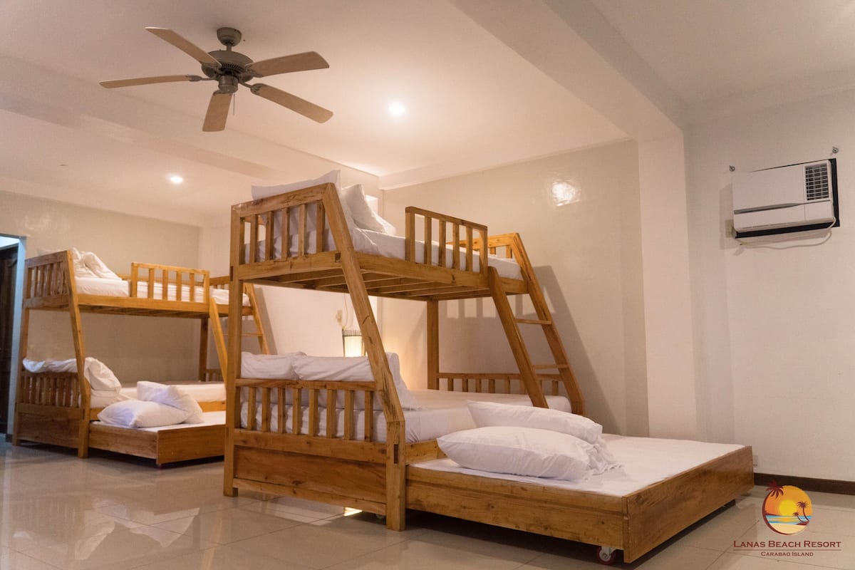 A room with bunk beds, a ceiling fan, and an air conditioning unit.