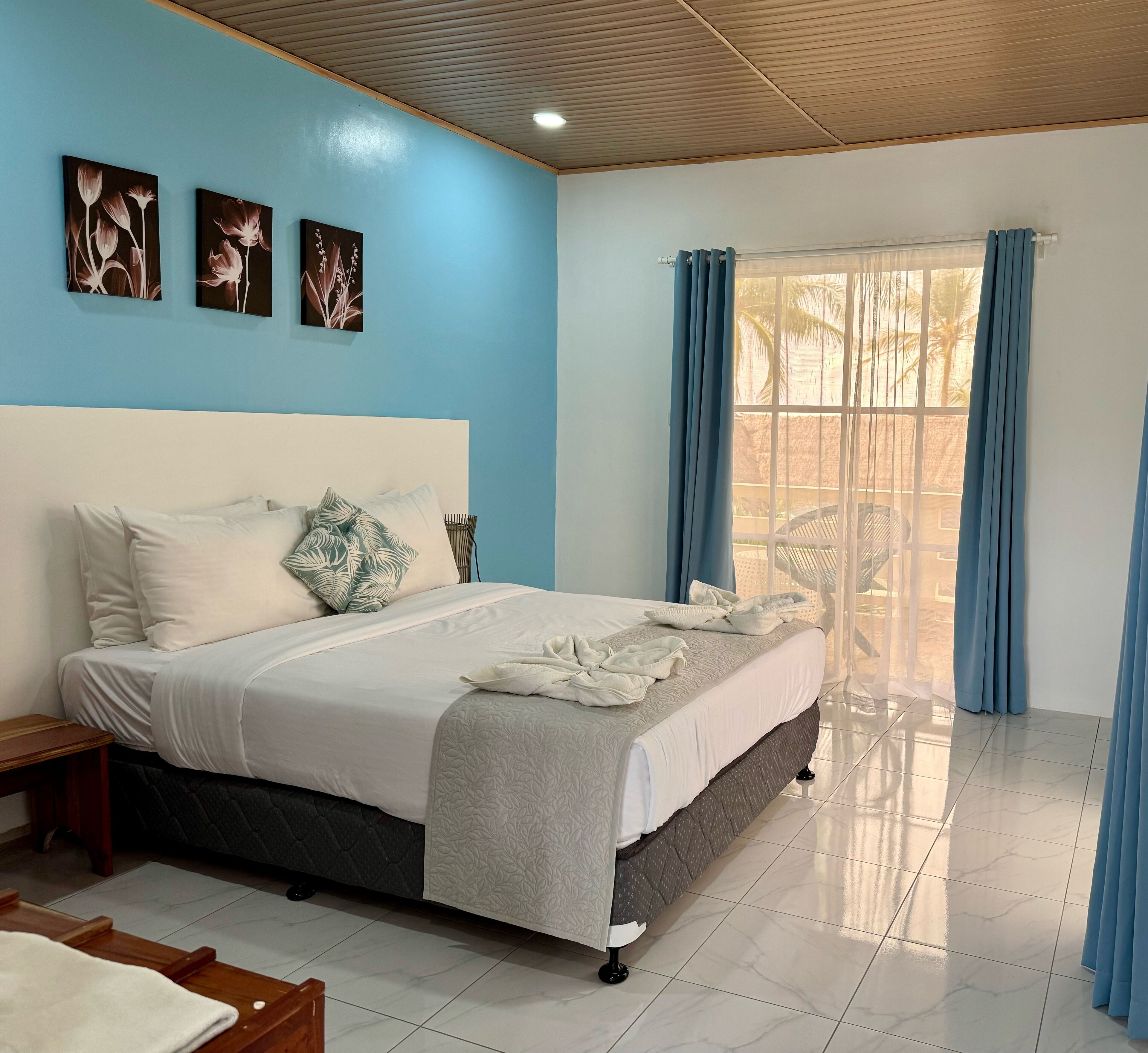 A bedroom with a bed, a nightstand, a window with curtains, and wall art.