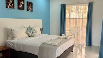 A bedroom with a bed, a nightstand, a window with curtains, and wall art.