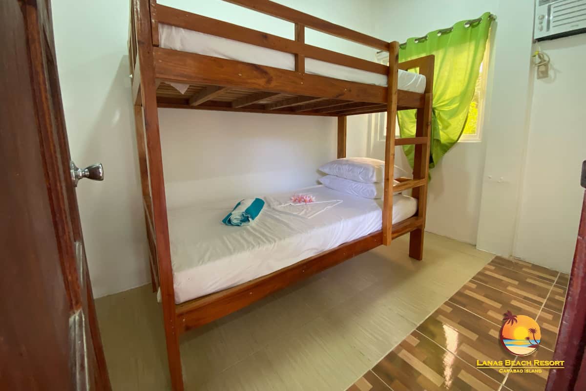 A bunk bed room with a wooden frame, a green curtain, and a tiled floor.