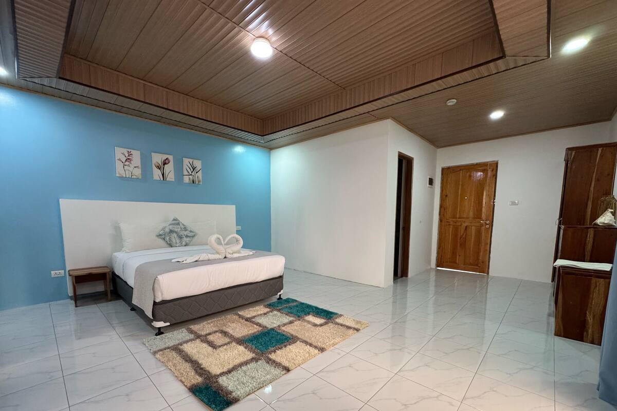 A bedroom with a bed, a nightstand, a wooden wardrobe, and a door.