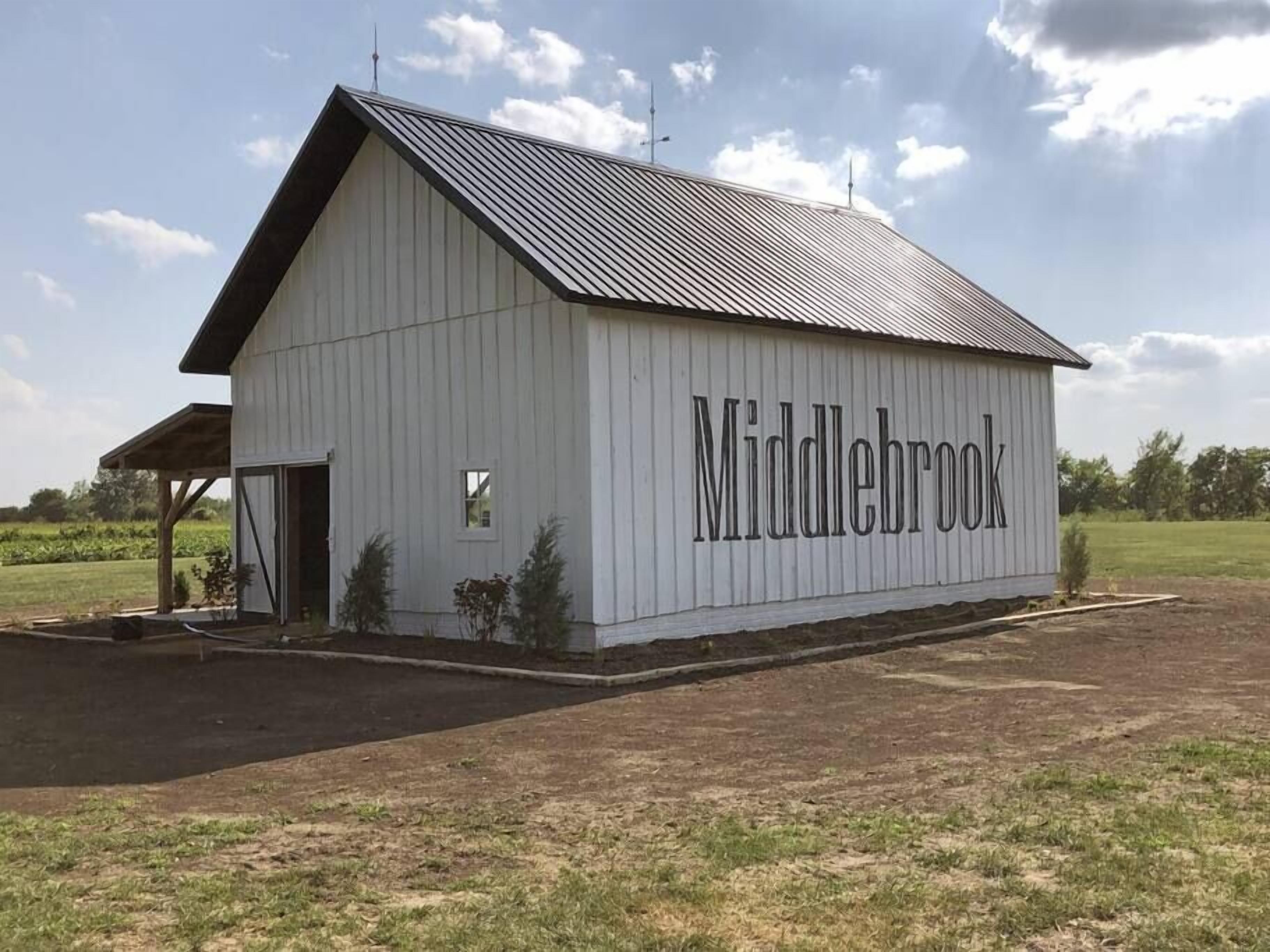 A white barn with the name "Middlebrook" on its side, a covered entrance, and a small window.