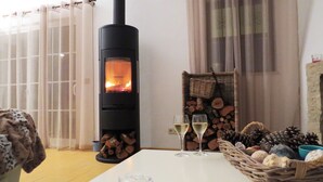 Una habitación acogedora con una estufa de leña, una mesa con vasos y una cesta de piñas.