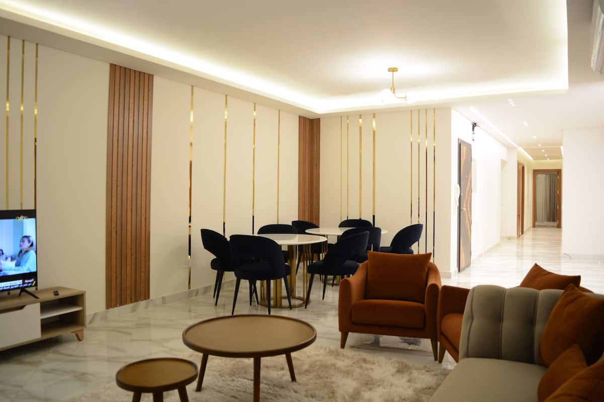 Una sala moderna con sofá, mesa de centro y comedor con sillas y televisor.