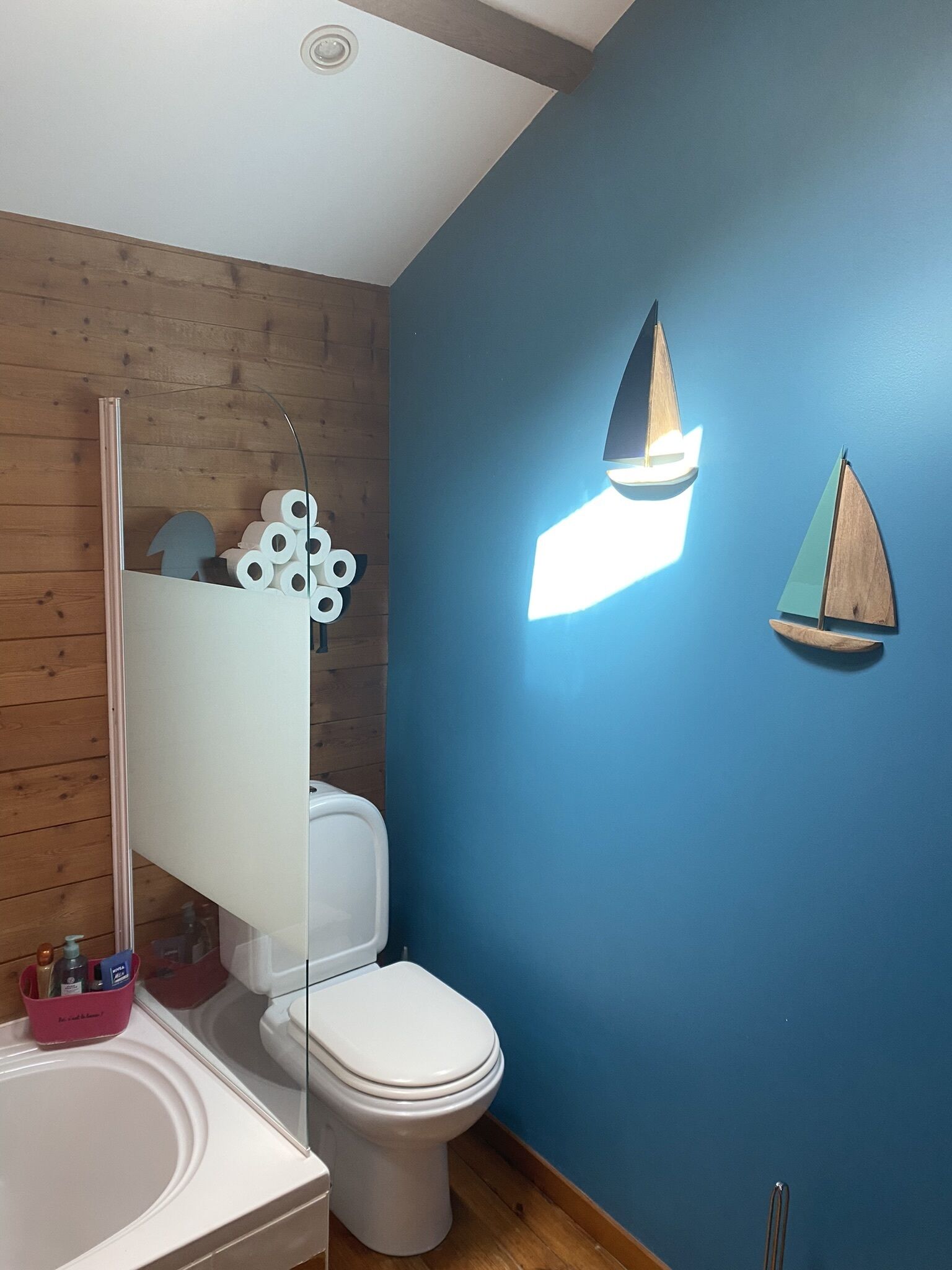 A bathroom with a wooden floor, a white toilet, a white sink, and a mirror.