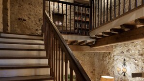 Eine rustikale Steintreppe mit Holzgeländern und einem Bücherregal oben.