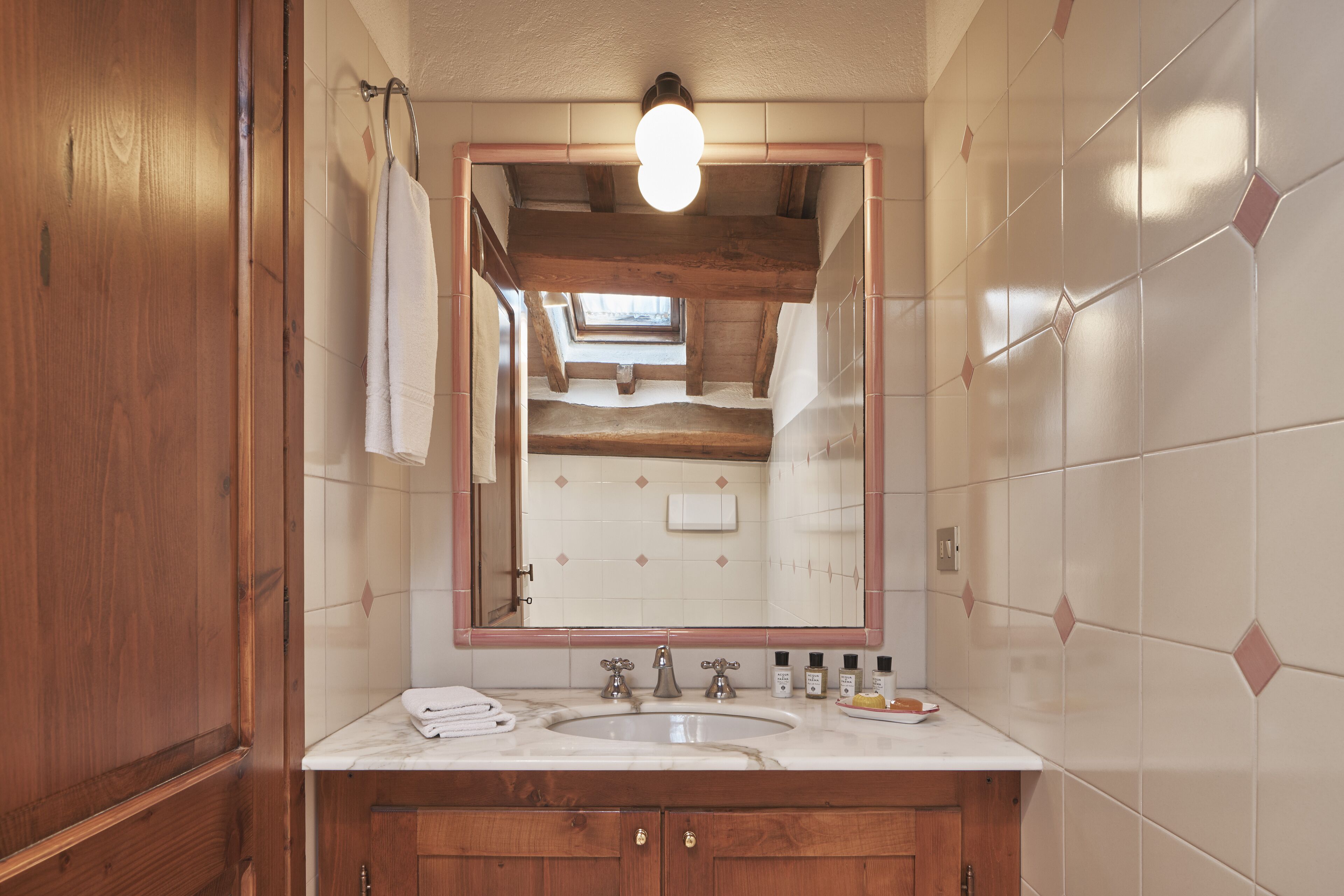 A bathroom with a wooden vanity, a large mirror, and a skylight above the sink.