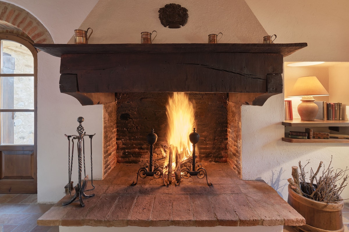 A fireplace with a stone surround, a wooden mantel, and a brick wall behind it.