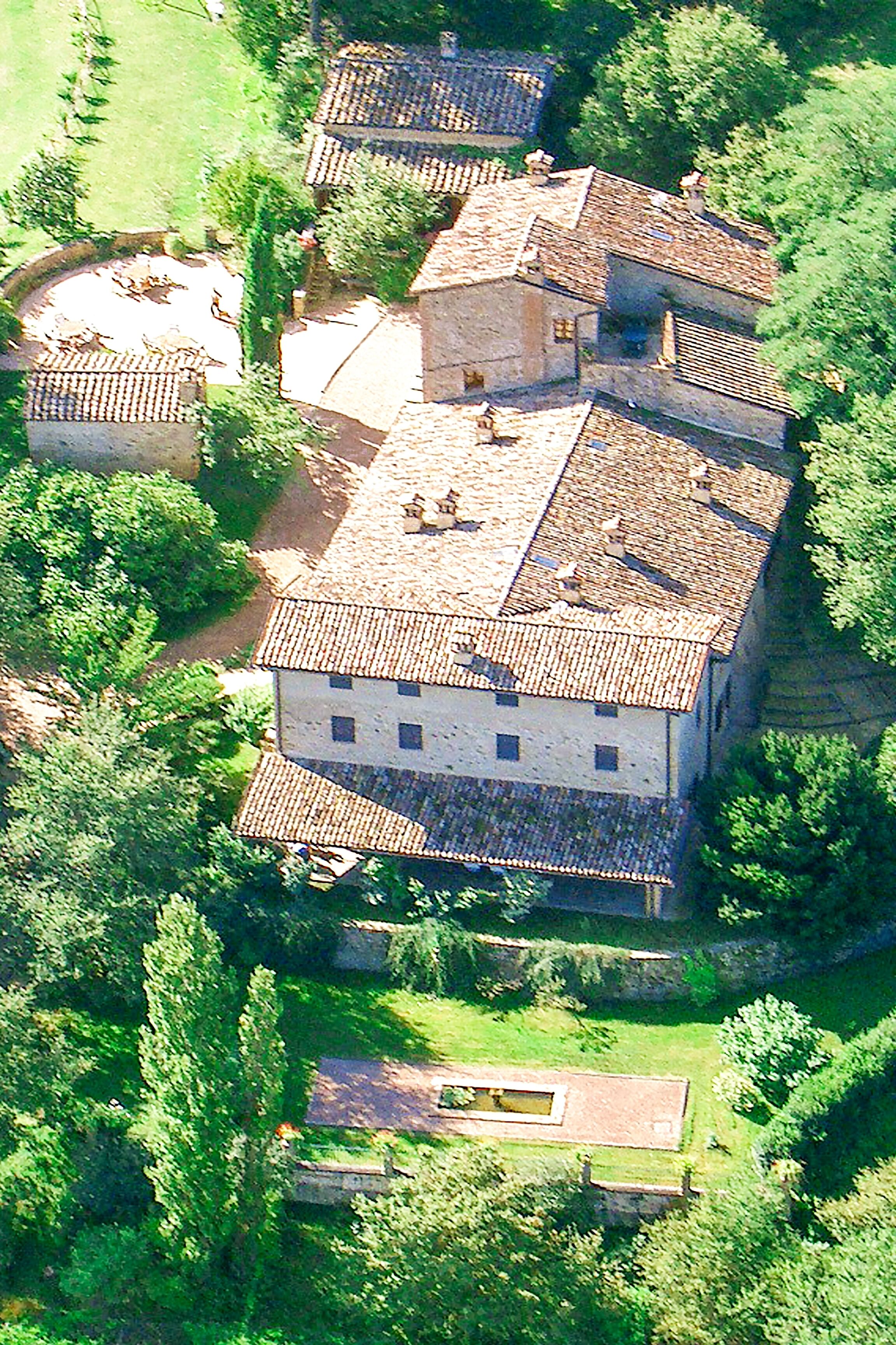 An aerial view of a historic building with multiple levels, surrounded by lush greenery.