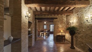 Ein rustikales Interieur mit freiliegenden Holzbalken, Steinwänden und einer Essecke mit Tisch und Stühlen.