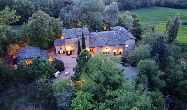 A large, multi-story house surrounded by dense trees and a green field. - Borgo il Poeta (Umbertide)
