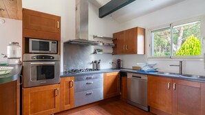 Une cuisine moderne avec des meubles en bois, des appareils en acier inoxydable et une fenêtre donnant sur un paysage verdoyant.
