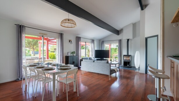 Un vaste espace de vie comprenant une table à manger pour six personnes, un canapé, un téléviseur et une cheminée.