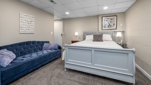 Un dormitorio con cama, sofá azul y obras de arte en las paredes.