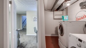 Un lavadero con lavadora, secadora y un cartel de servicio de lavandería.