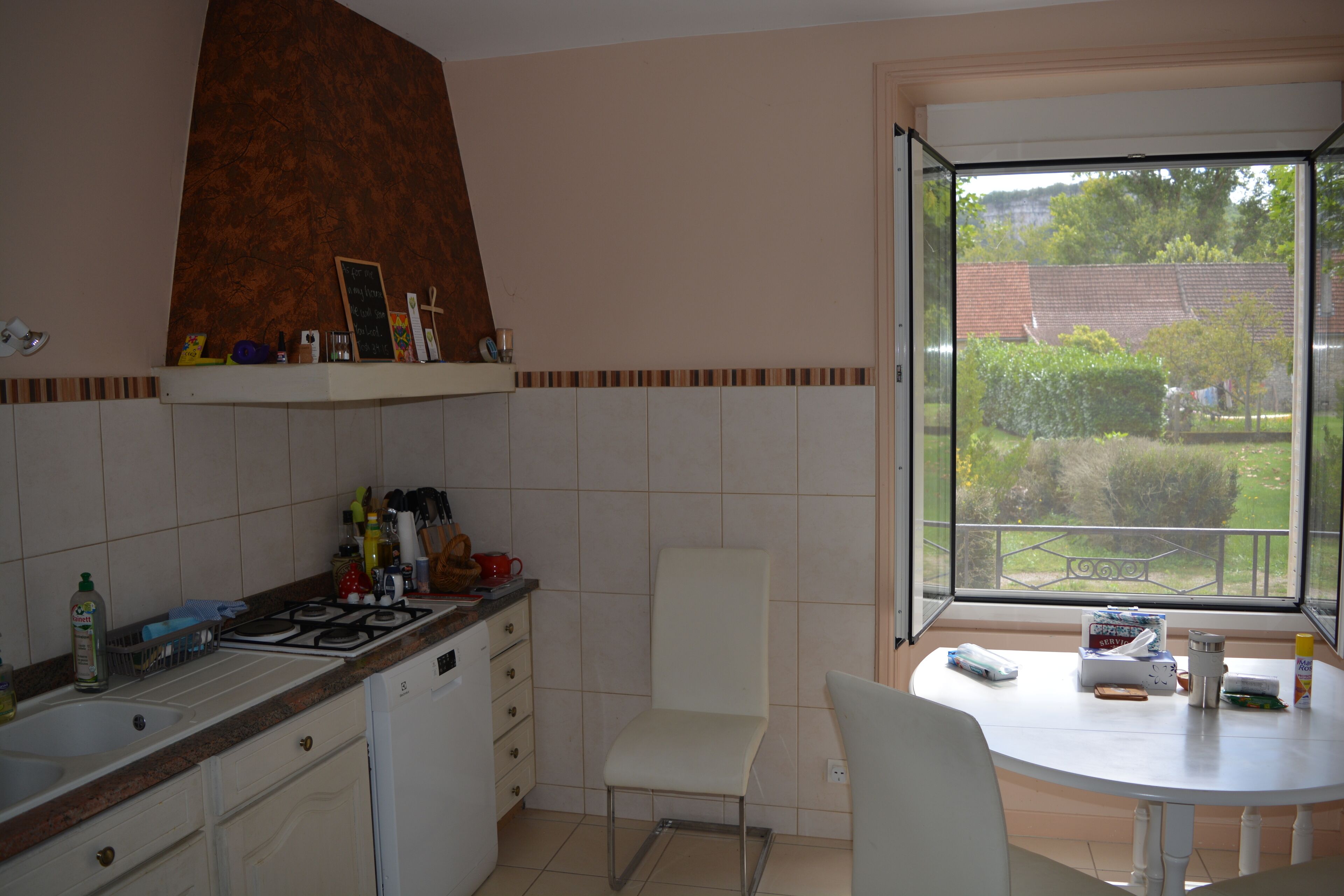 A kitchen with a stove, sink, and a dining table with chairs.