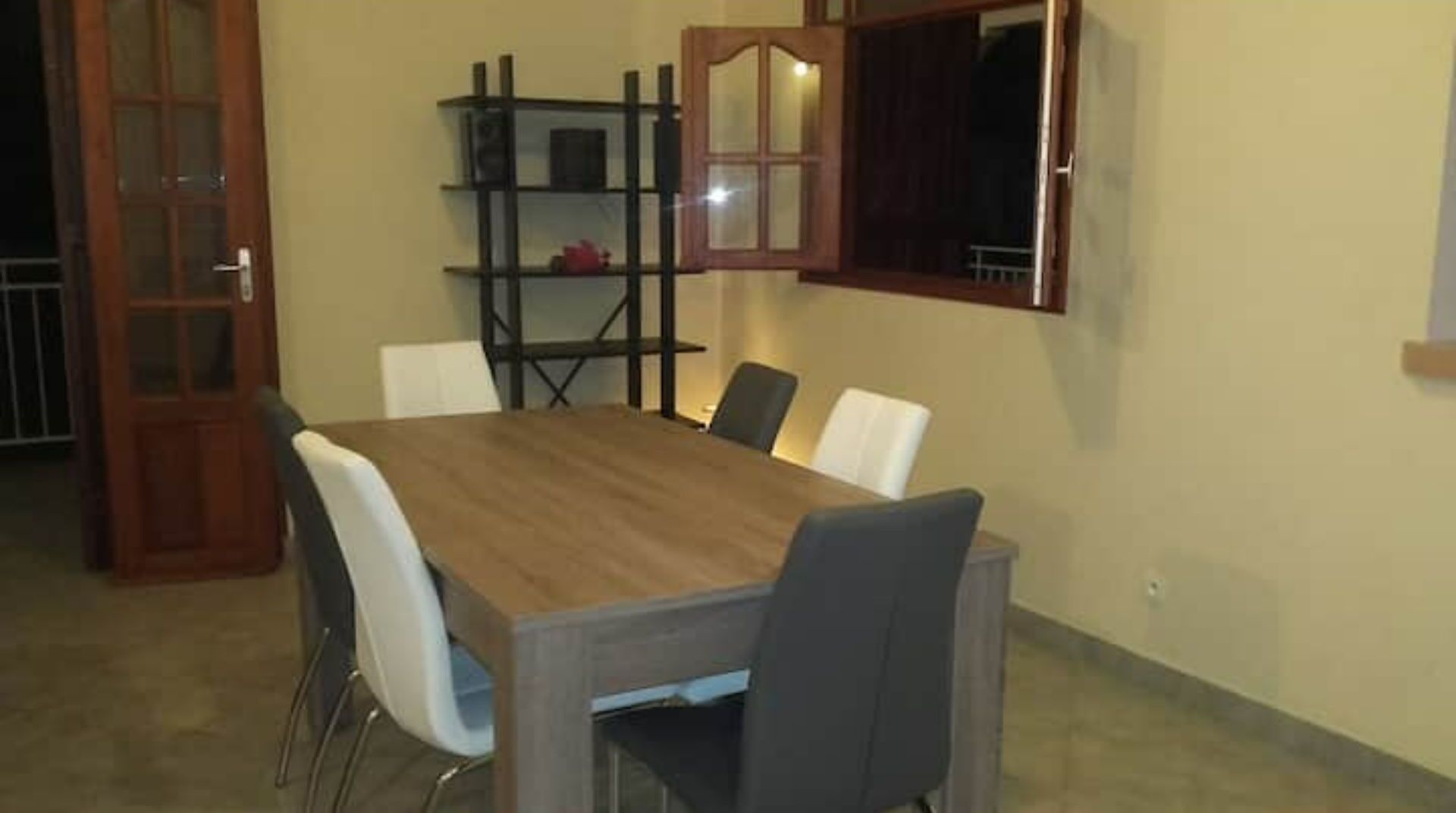 A dining area with a wooden table and white chairs.
