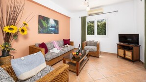 A living room with a sofa, armchairs, a coffee table, a TV, and a painting on the wall.