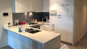 Una cocina moderna con armarios blancos, una isla central con pileta, estufa y microondas.