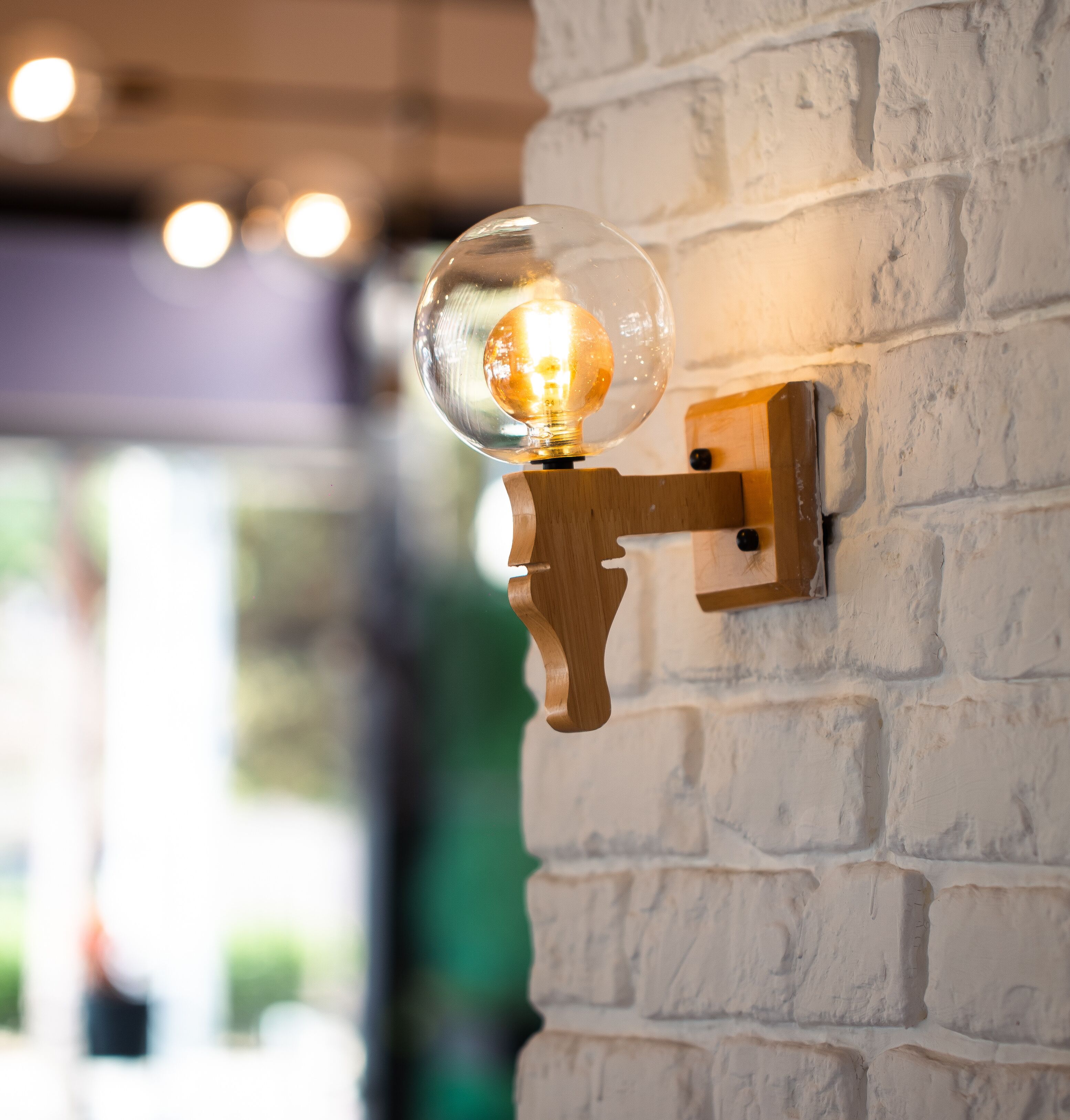 Un luminaire mural doté d’un globe en verre transparent et d’un socle en laiton.