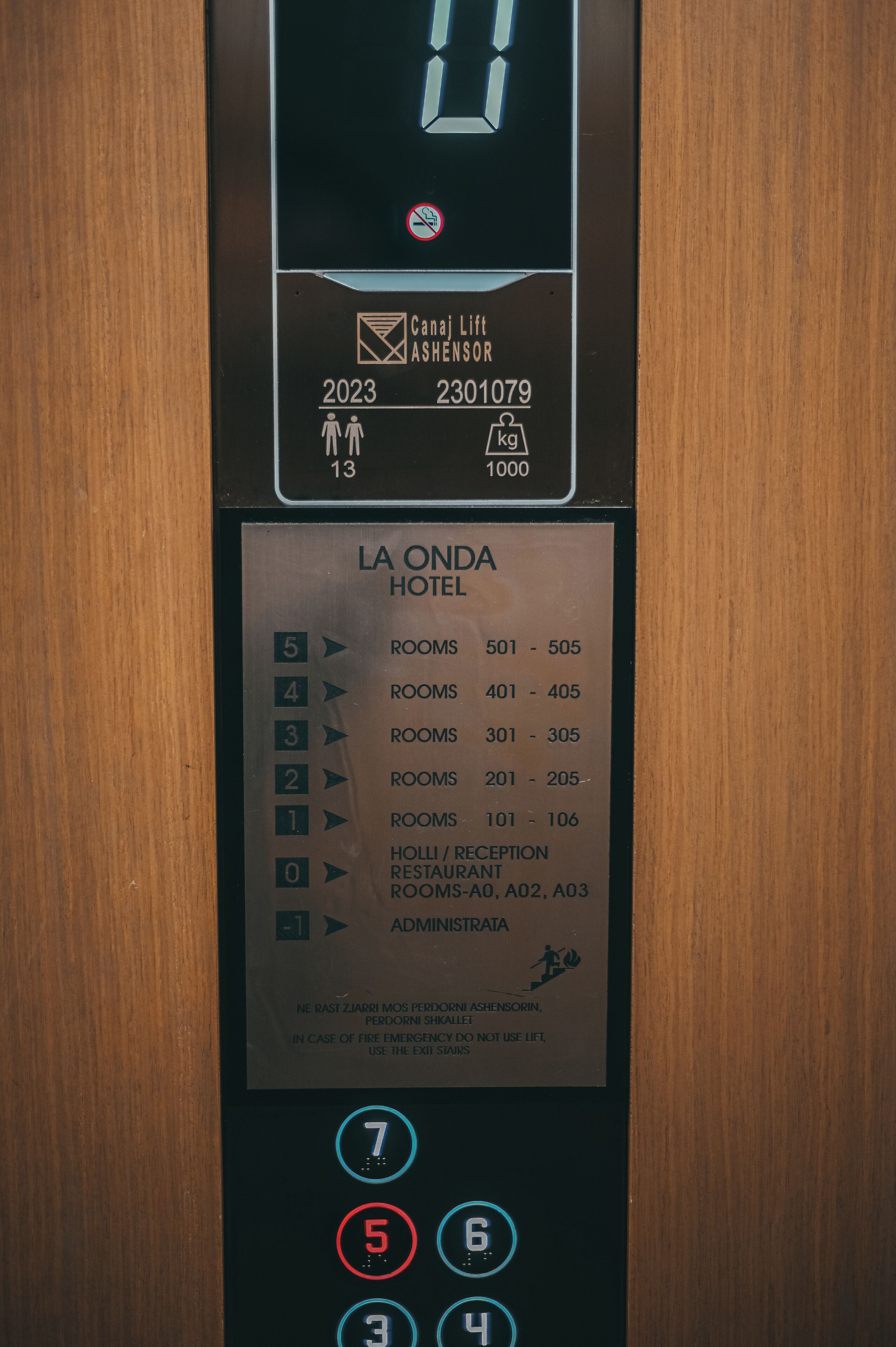 An elevator control panel with floor selection buttons, a digital display, and a hotel directory.