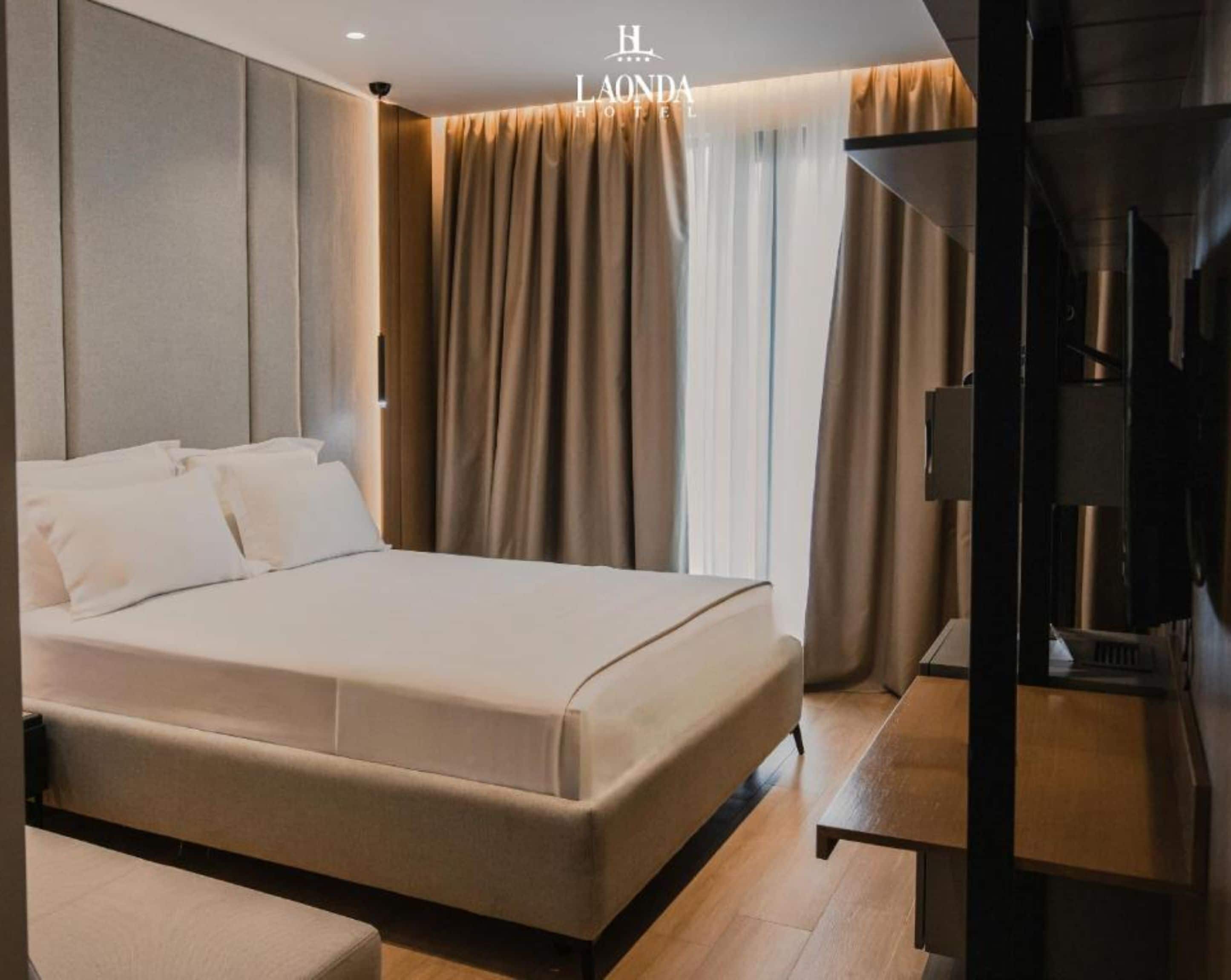 A modern hotel room with a large bed, a flat-screen TV, and a sofa.