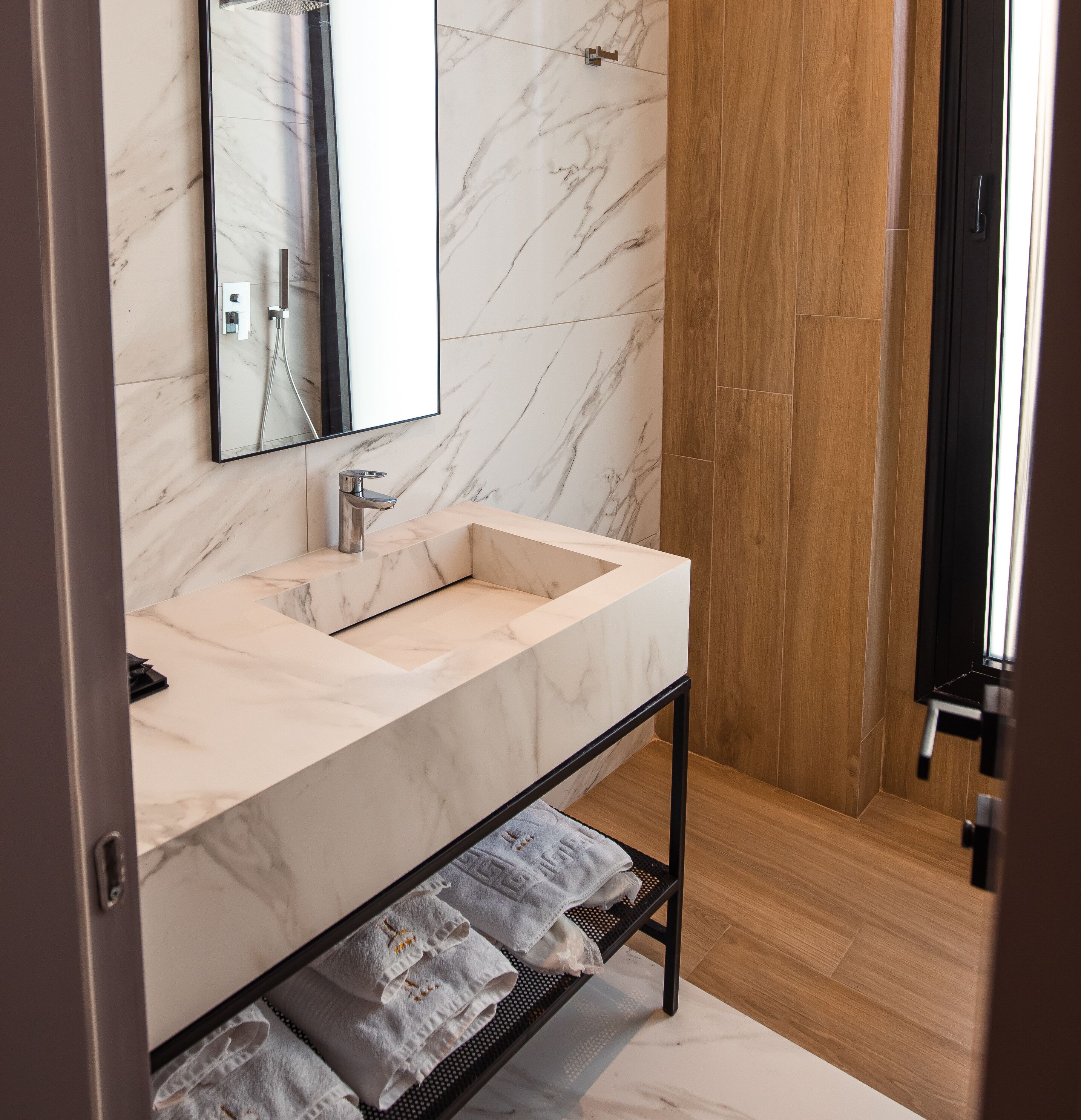 Une salle de bain moderne avec un lavabo en marbre, un miroir et un plancher en bois.
