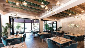 A restaurant with tables set for dining, a decorative ceiling, and a wall with the hotel's name. - La Onda Hotel (Durrës)