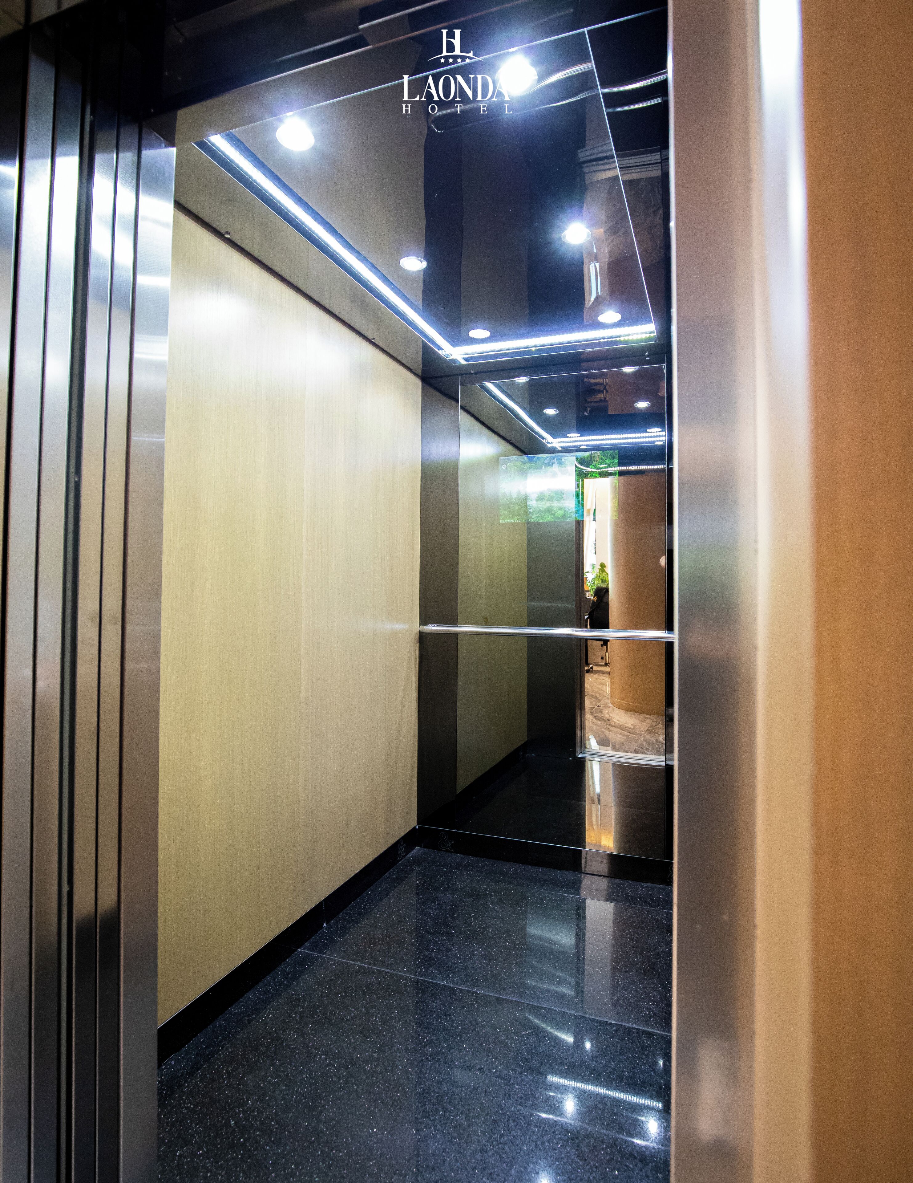 Vista del interior de un moderno ascensor con paredes metálicas y un suelo reflectante.