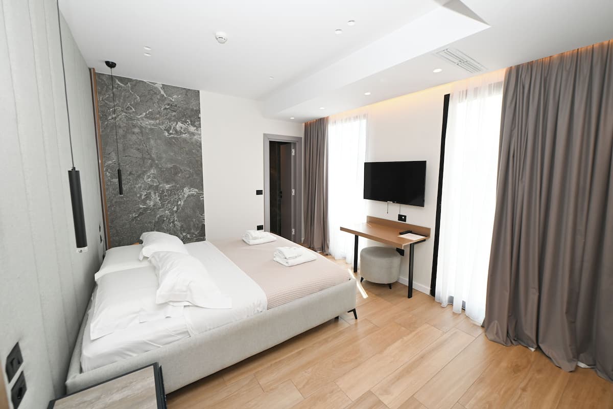 Una habitación de hotel moderna con una cama grande, un escritorio, un televisor de pantalla plana y vistas a la ciudad.