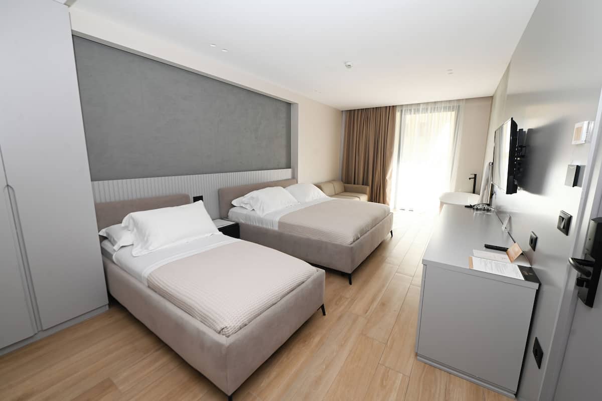 Habitación de hotel con dos camas, un escritorio, un televisor y un minibar.
