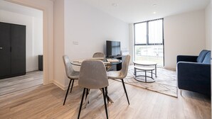 A modern living room with a dining area, a sofa, and a TV. - GuestReady - Lux getaway in Liverpool (Liverpool)
