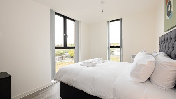 A bedroom with a large bed, two windows, and a view of the outdoors. - GuestReady - Lux getaway in Liverpool (Liverpool)