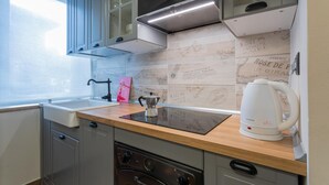 Een keuken met een houten aanrecht, een ingebouwde kookplaat, een waterkoker en een raam.