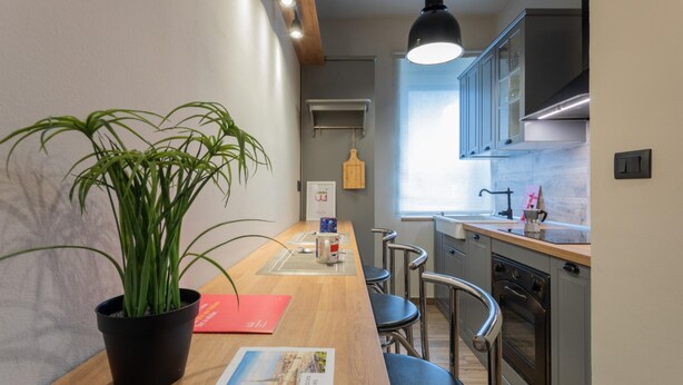 Een moderne keuken met een houten aanrecht, roestvrijstalen apparatuur en een hanglamp.