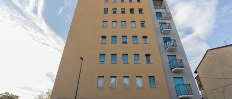 Ein mehrgeschossiges Gebäude mit einer beige farbenen Fassade, mehreren Balkonen und einem sichtbaren Eingang.
