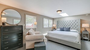 Une chambre à coucher avec un lit, une commode, une chaise et un grand miroir.