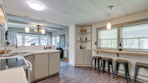 Une cuisine moderne dotée d’un îlot central, de tabourets de bar et de luminaires suspendus.