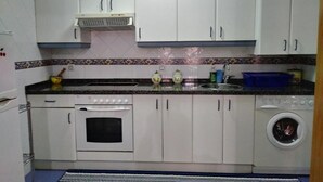 A compact kitchen with white cabinets, a built-in oven, a washing machine, and a microwave. - Loft Amplio con Garaje en Calle Rey Aurelio en Cangas de Onís (Cangas de Onís)
